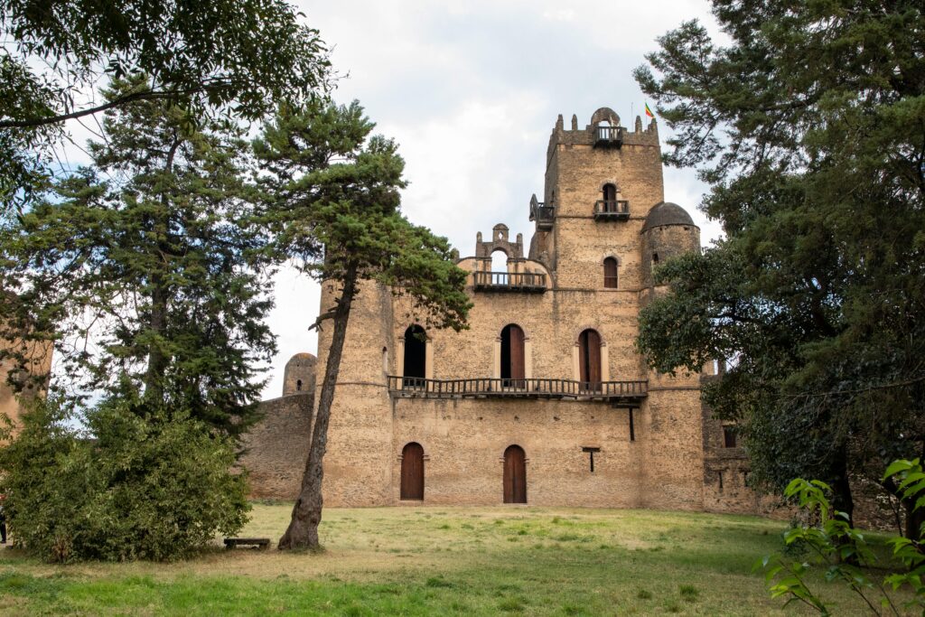 Explore the historic Fasil Ghebbi castle in Gondar, Ethiopia, surrounded by lush greenery.